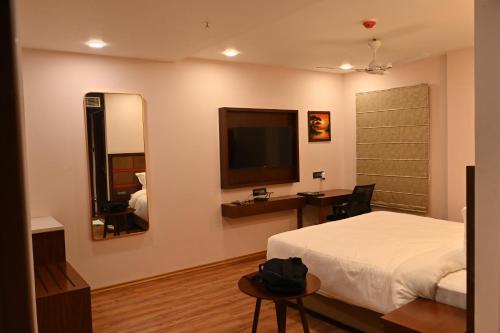 a bedroom with a bed and a television on the wall at HOTEL NILACHAL - 10 Mins Travel to Kamakhya Temple, Guwahati in Guwahati