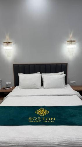 a bed with a green and white blanket on it at Boston Grand hotel in Osh