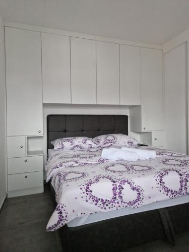 a bedroom with a bed with purple flowers on it at Stan na dan - Brcko 1 in Brčko