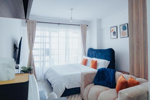 a bedroom with a bed and a couch and a window at Work Friendly Studio near Nairobi CBD and Westlands in Nairobi