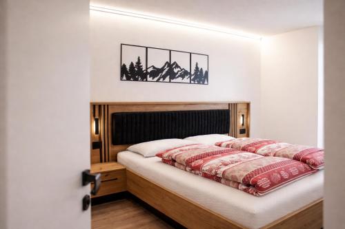 a bedroom with a bed with a wooden headboard at MOUNTAIN HOME Fiemme - Nuovo, Balconi e Garage in Castello di Fiemme