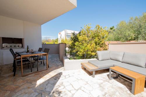 a patio with a couch and a table and chairs at Laurentina - Modern Apartment with Large Terrace near Beach-quiet and comfortable in Sutivan