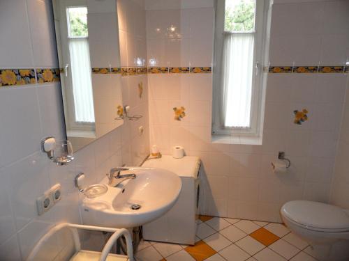 a white bathroom with a sink and a toilet at Ferienwohnungen direkt am Schmollensee in Bansin