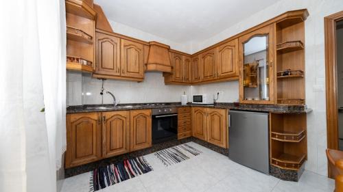 a kitchen with wooden cabinets and a black dishwasher at Langosteira Beach, spacious apartment in Fisterra