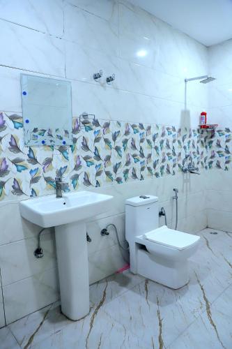 a white bathroom with a sink and a toilet at The Golden Farm in Jāmb