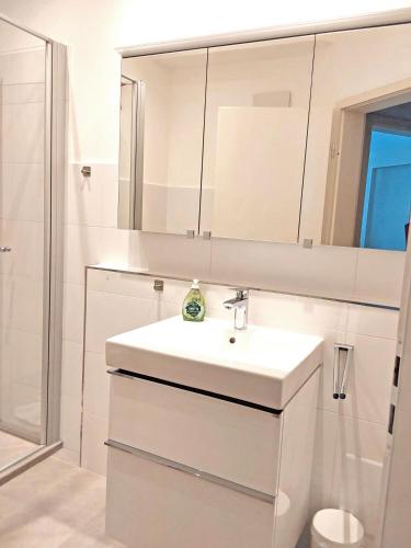a white bathroom with a sink and a mirror at Ferienwohnung Schwark Haus Elisabeth in Aschau im Chiemgau
