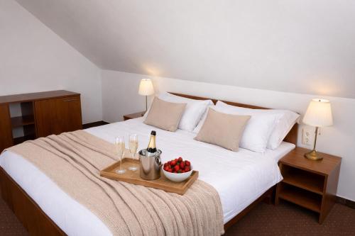 a bed with a tray of fruit and a bottle of wine at Penzión Lapáš u Hoffera in Nitra