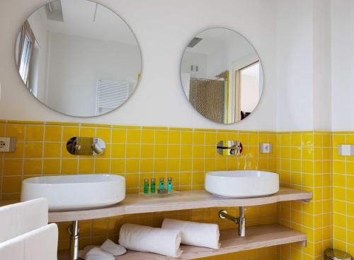 two sinks in a yellow tiled bathroom with mirrors at Borgo Sant'Anna in Amalfi
