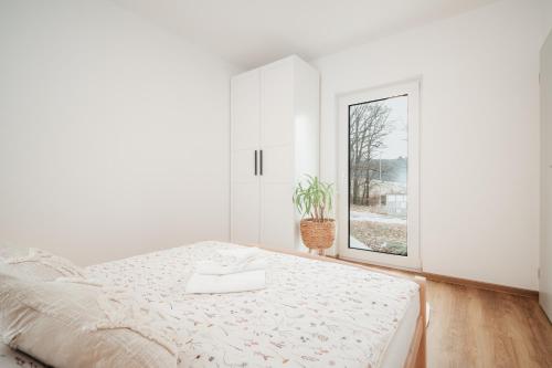 a white bedroom with a bed and a window at Domeček U Potoka in České Budějovice