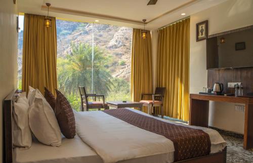 a hotel room with a bed and a large window at BADIGARH RESORT - Udaipur in Thūr