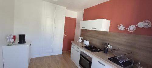 a kitchen with red and white walls and a counter at F2 plages du débarquement rénové in Grandcamp-Maisy