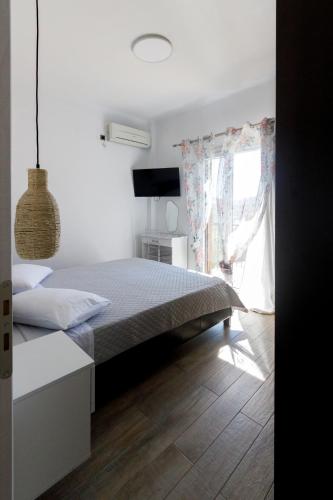 a white bedroom with a bed and a window at La casa nel campo in Syros Island National Airport