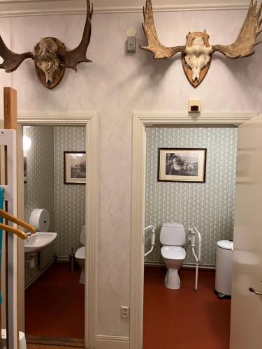 a bathroom with a toilet and antlers on the wall at Lantlivlodge i Österjörn -Herrgård in Österjörn