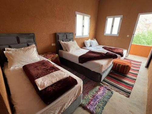 a bedroom with two beds and a room with windows at Pergolas Tamakoucht in Ouarzazate