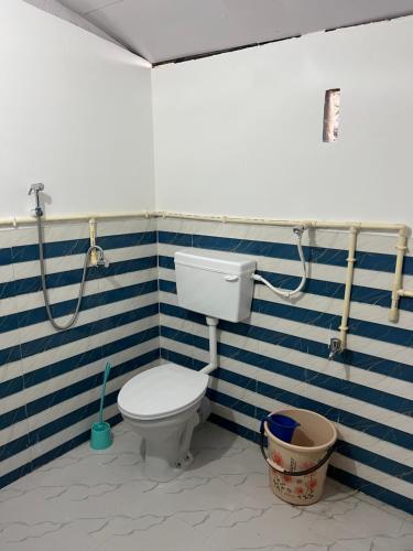 a bathroom with a toilet and a blue and white striped wall at Jumusing homestay in Rupa