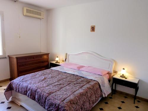 a bedroom with a bed with pink pillows and two tables at Casa vacanze sa minda noa whit a private garden in Olbia
