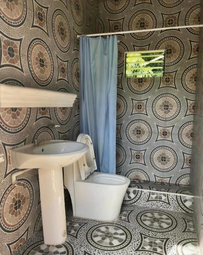 a bathroom with a toilet and a sink at Penoria's lodge kubo in Mambajao