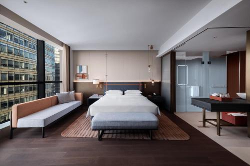 a bedroom with a bed and a couch and a piano at 苏州云启一方酒店-凯悦尚选 in Suzhou