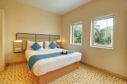 a bedroom with a large bed and two windows at Hotel Vilmaris Breeze in Calangute