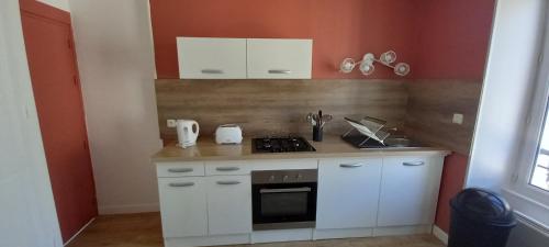 a small kitchen with white cabinets and a stove at F2 plages du débarquement rénové in Grandcamp-Maisy