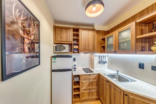 a kitchen with wooden cabinets and a refrigerator at Ember Suite 1BR - Mountain Lake Complex By Flat Mаnager in Smolyan
