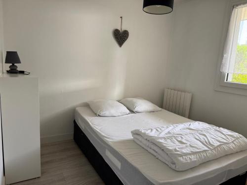 a bed in a bedroom with a heart on the wall at T2 jardinet, accès direct plage in Cabourg