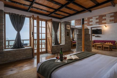 a bedroom with a bed with two glasses of wine at THE CEDAR CASTLE in Mukteshwar