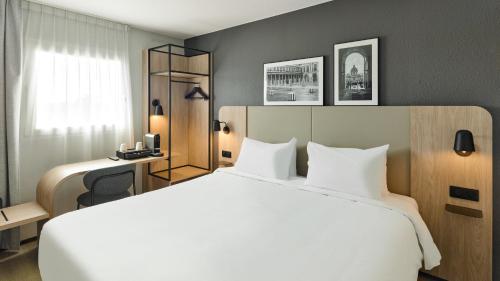a hotel room with a large white bed and a desk at Campanile PRIME - Paris - Porte de Bagnolet in Bagnolet