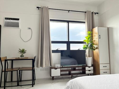 ein Schlafzimmer mit Bett, Schreibtisch und Fenster in der Unterkunft Luxee Haven in Manila
