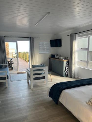 a bedroom with a bed and a desk and a balcony at Net Genoeg in De Kelders