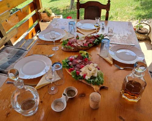 a wooden table with plates of food and wine glasses at Ramaća House in Ramaća