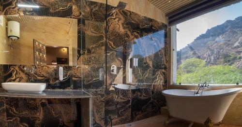 a bathroom with a tub and a sink and a window at BADIGARH RESORT - Udaipur in Thūr