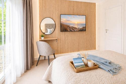 a bedroom with a bed with a mirror and a chair at Villa Manatee mit Sauna & Fitness in Ostseebad Sellin
