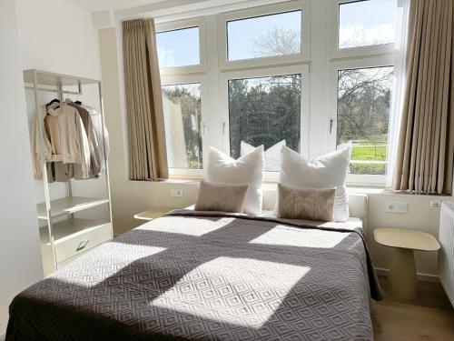 a bedroom with a bed with pillows and a window at ME LIVING Villa am Kurpark - Design Apartments in Bad Salzuflen