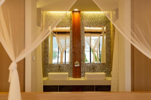 a bathroom with two sinks and a mirror at The Cozy Beachfront Phuket in Patong Beach