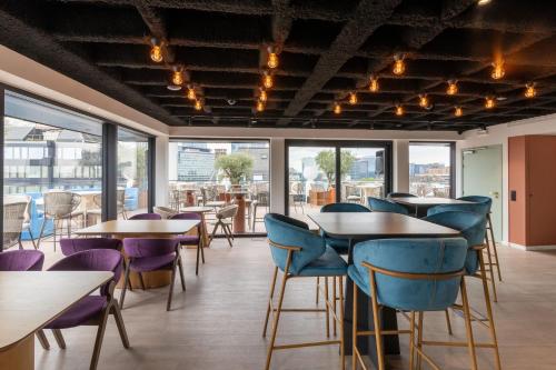 een restaurant met tafels, stoelen en ramen bij The Liman Hotel in Brussel