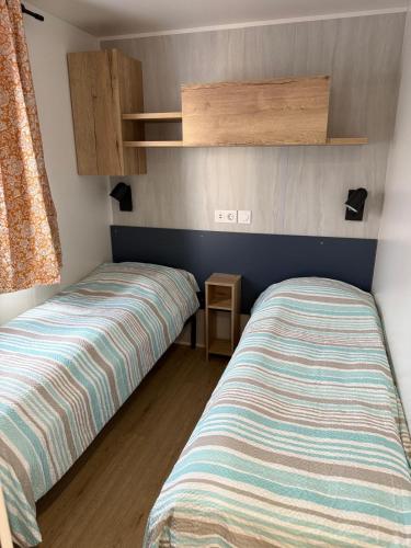 two beds in a small room with a bedskirtsermottermott at Finca Leberto in Renesse