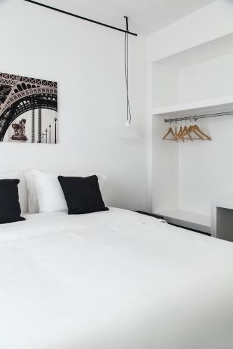 a white bedroom with a white bed with black pillows at Hotel Alto San Isidro in San Isidro