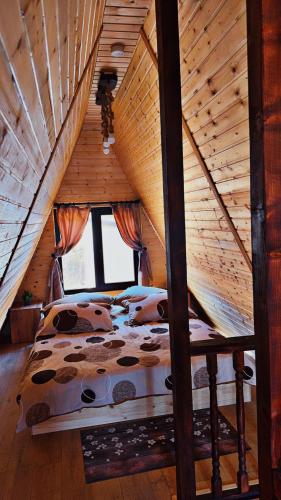 a bedroom with a bed in a wooden attic at Căsuțele EliMar in Chirleşti