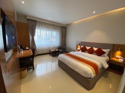 a bedroom with a bed and a desk and a television at Landmark Narayani in Chitwan