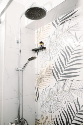 a shower in a bathroom with black and white leaves wallpaper at Nuance Residences - Cresento in Volos