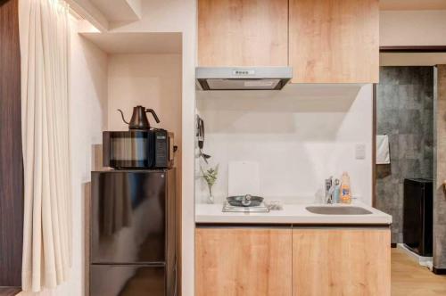 a small kitchen with a refrigerator and a sink at YCYC Hotel in Tokyo