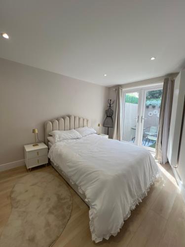 a white bedroom with a large bed and a window at Brand New One Bedroom Apartment in Hendon