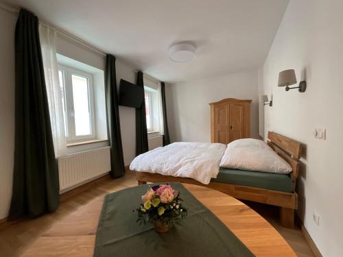 a bedroom with a bed and a table with flowers on it at Ferienwohnung historisches Teisendorf in Teisendorf