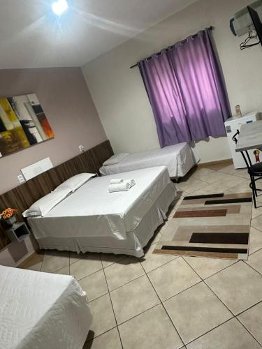 a bedroom with two beds and a purple window at Itaipu Hotel in Foz do Iguaçu