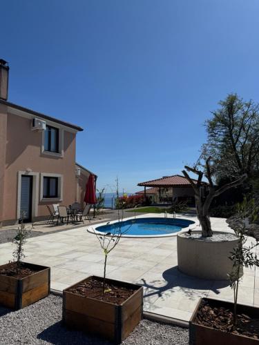 a patio with a swimming pool and two potted plants at Villa Petra in Kastav