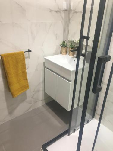 a bathroom with a white sink and a yellow towel at Casa BeijoMar in Nazaré