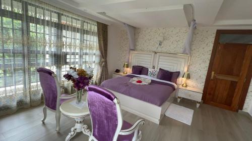 a bedroom with a purple bed and a table with purple chairs at Silva Montana in Mount Kenya
