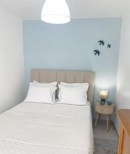 a bedroom with a bed with white sheets and pillows at Casa BeijoMar in Nazaré