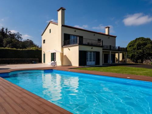 a villa with a swimming pool in front of a house at Quinta da Lu - Azorean Villa in Ribeira Grande